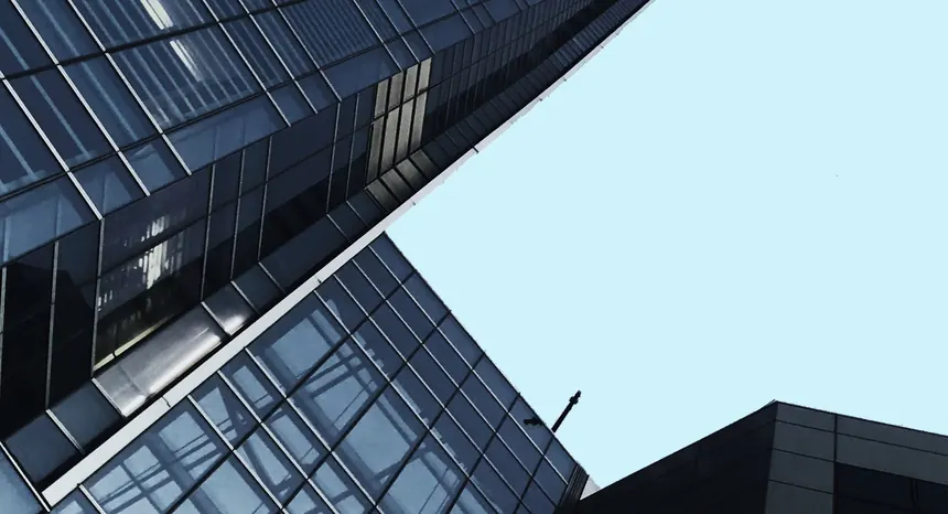 Looking up at a glass office tower against a pale sky