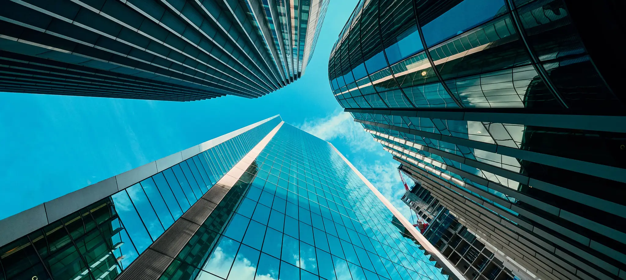 Looking up between glass office towers to the sky
